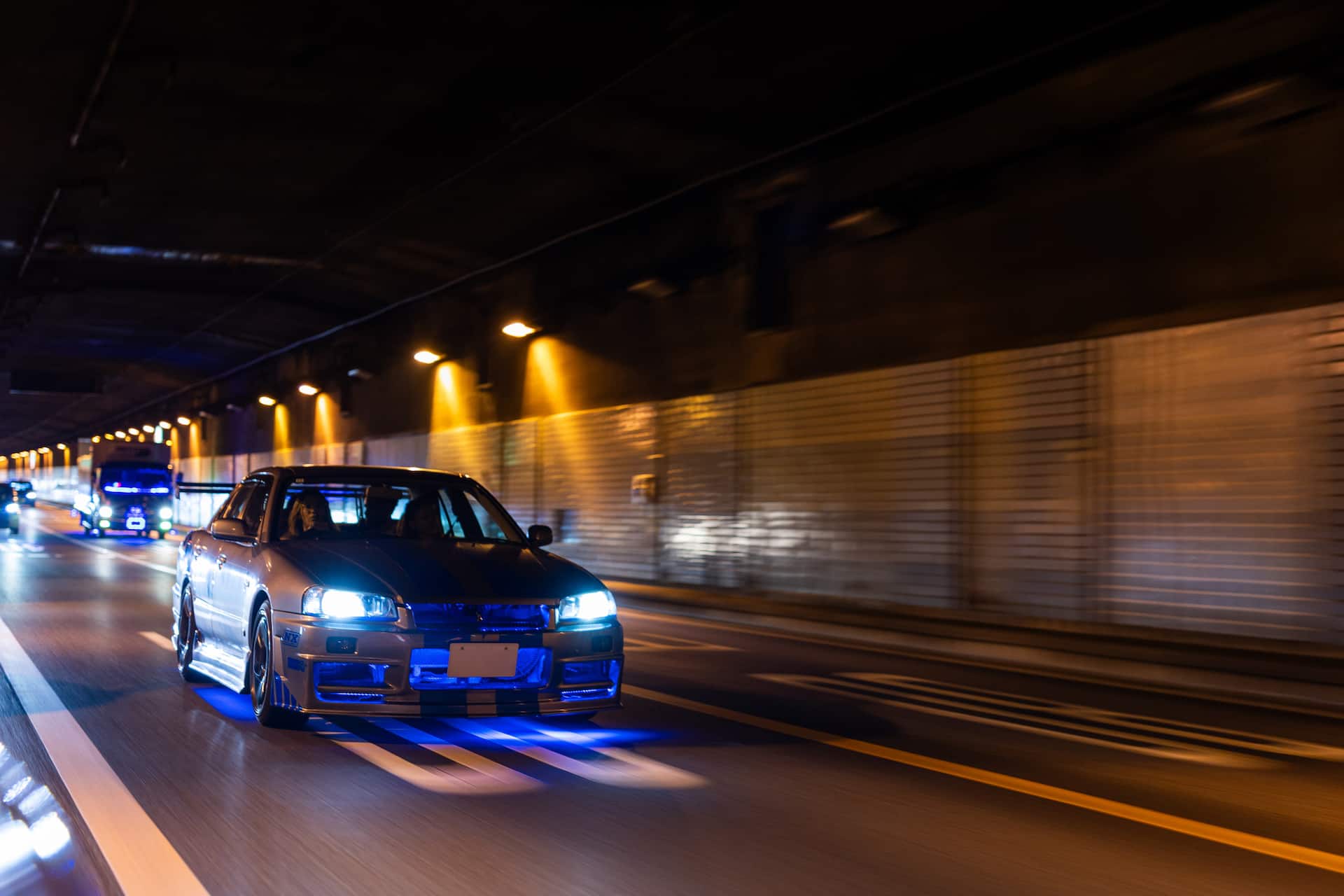 Silver Nissan Skyline GT-R driving through Tokyo at night
